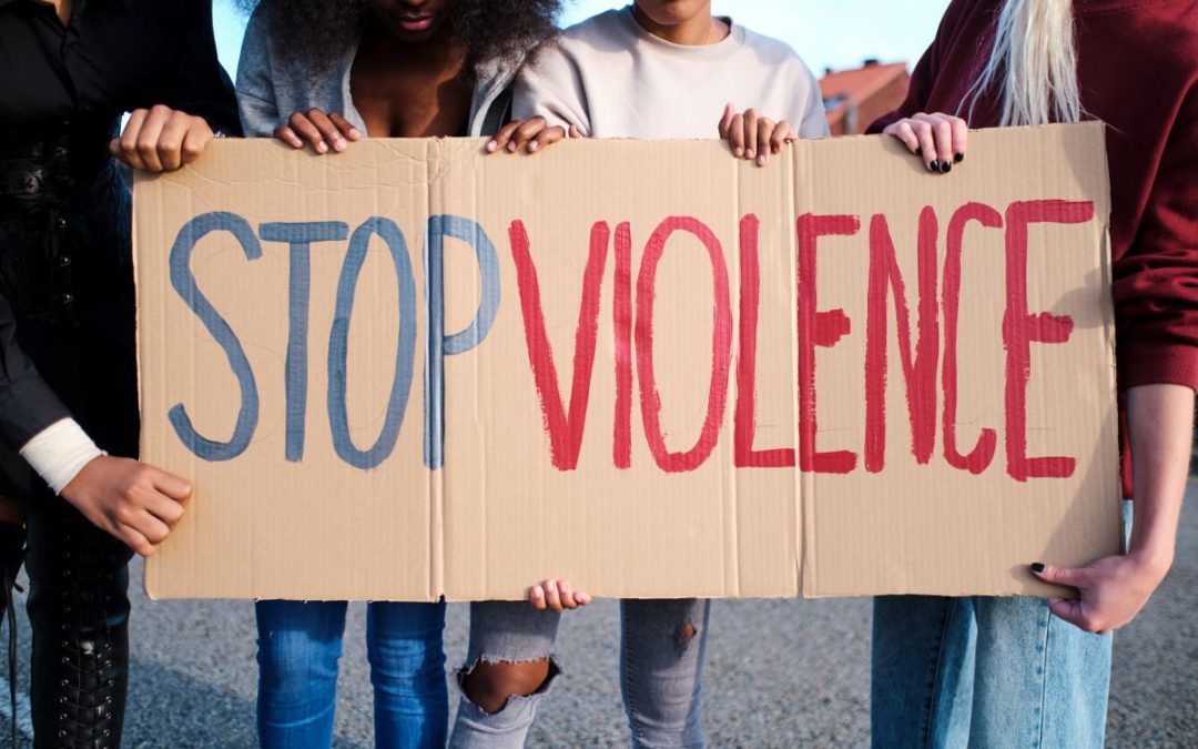 group of women holding a sign that says STOP VIOLENCE