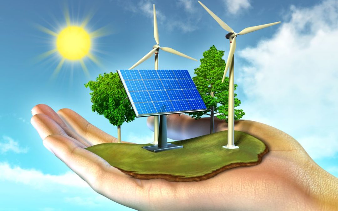 A person is holding a piece of land in their hand that contains greenery, a solar panel and wind turbines with a sun on the left side to show renewable energy.