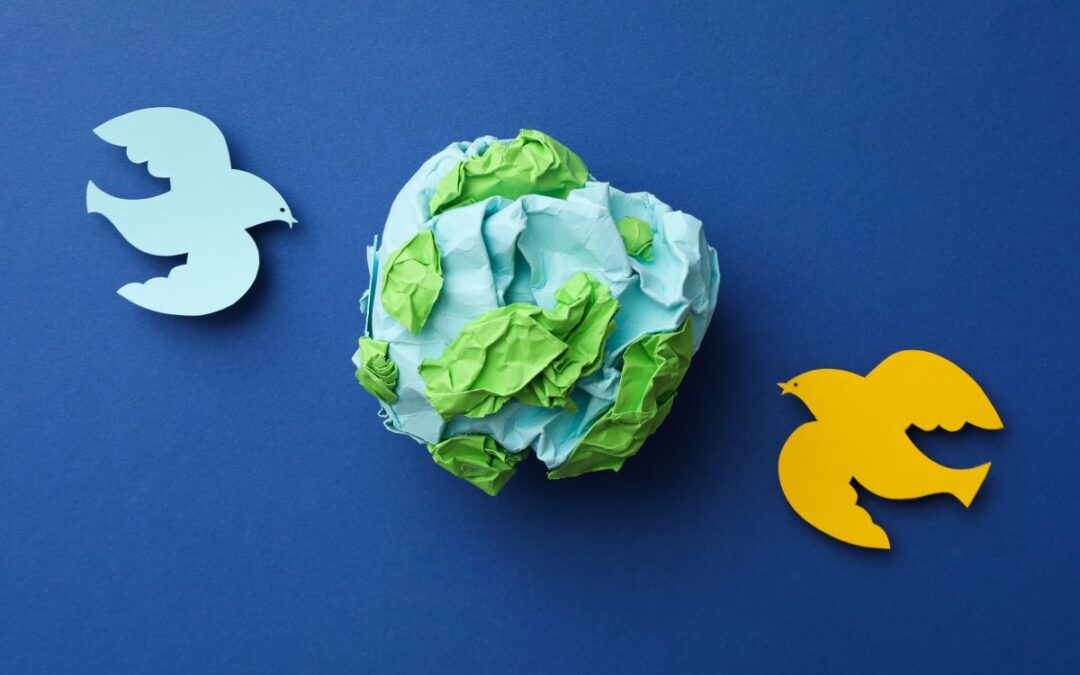 two paper doves (one blue and one yellow) surrounding a paper earth to indicate International Day of Peace