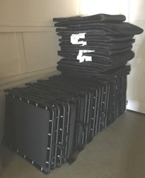 Stack of folded black chairs stored in a room.