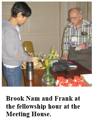 A young man and an elderly man arrange flowers on a table during a fellowship hour at a meeting house.